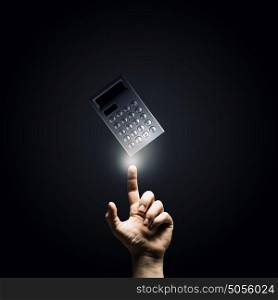 Accounting concept. Close up of male hand pointing at calculator