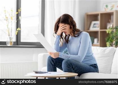 accounting, taxes and finances concept - stressed young woman with papers and calculator at home. stressed woman with papers and calculator at home