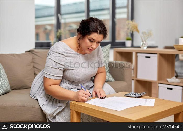 accounting, taxes and people concept - woman with bills or papers and calculator at home. woman with bills or papers and calculator at home