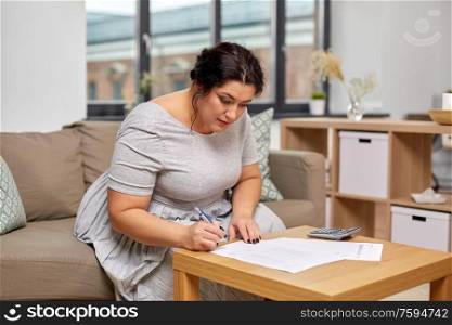 accounting, taxes and people concept - woman with bills or papers and calculator at home. woman with bills or papers and calculator at home
