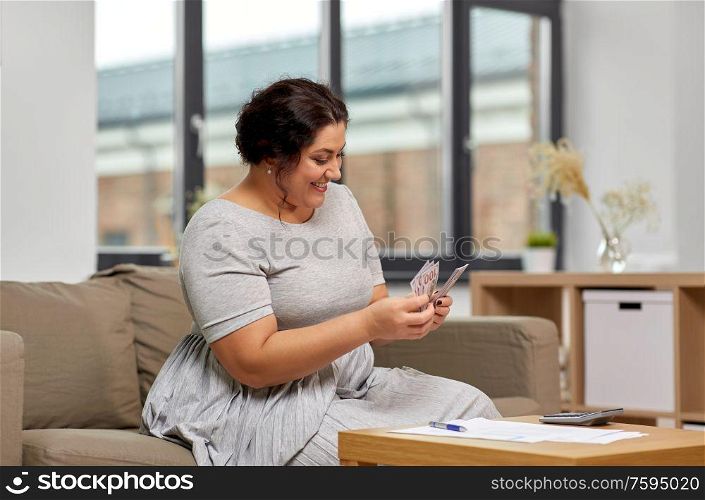 accounting, taxes and people concept - woman with money, papers and calculator at home. woman with money, papers and calculator at home