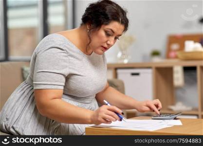 accounting, taxes and people concept - woman with papers and calculator working at home. woman with papers and calculator working at home