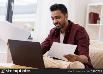 accounting, technology and people concept - confused man with laptop computer and papers at home. confused man with laptop and papers at home