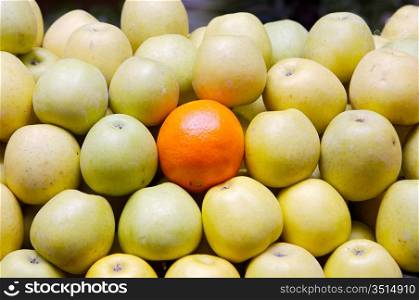 accumulated apples whit a orange in a store of fruits
