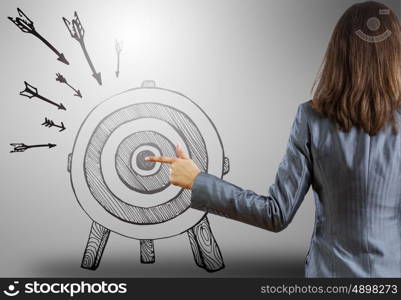 Achieving goals. Rear view of businesswoman pointing at drawn target