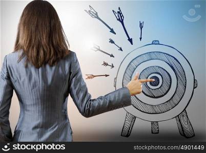 Achieving goals. Rear view of businesswoman pointing at drawn target