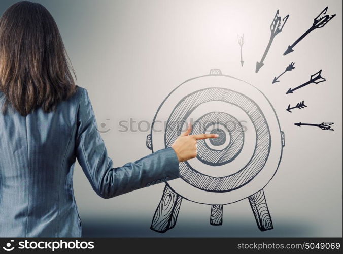 Achieving goals. Rear view of businesswoman pointing at drawn target