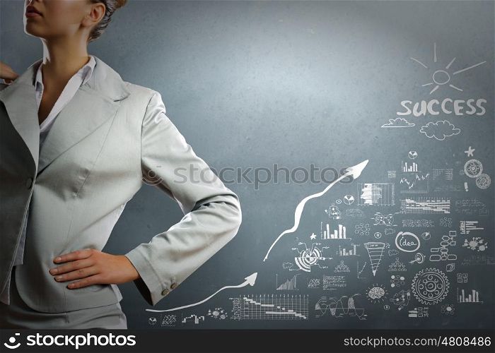 Achieving success. Close up of businesswoman and business sketches on cement wall