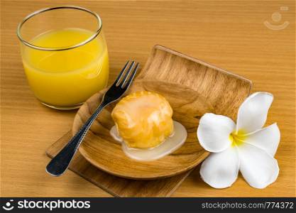Aclair topped with sweet condensed milk in wooden plate with a glass of passion fruit juice on wooden table