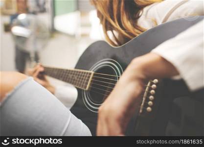 Acoustic guitar details in the hand of a left-handed woman