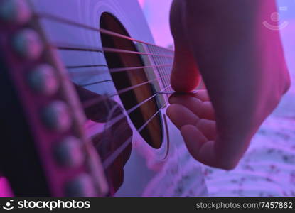 Acoustic guitar played by a girl and colorful lights