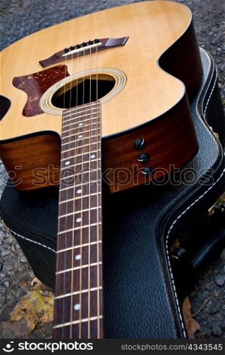 Acoustic guitar sitting on it&acute;s closed case.