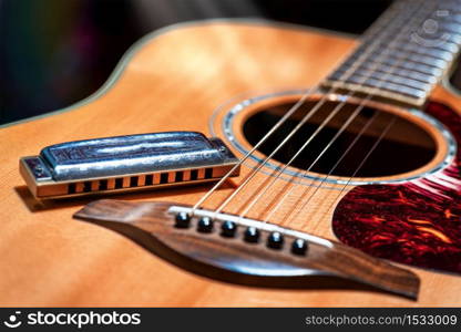 Acoustic guitar with country blues harmonica ready on stage