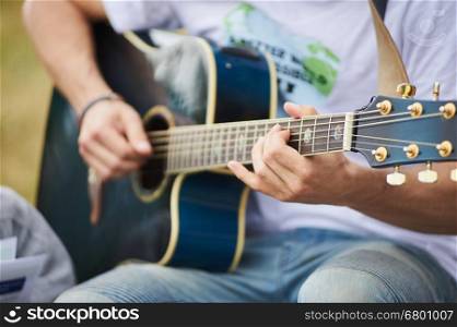 Acoustic guitarist. Young man playing blue acoustic guitar. Summer outside.