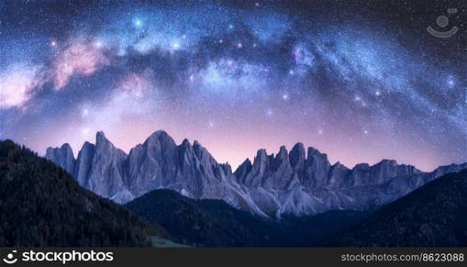 Acrhed Milky Way over beautifull rocks at starry night in summer in Dolomites, Italy. Purple sky with stars and bright milky way arch over high alpine rocky mountains. Space background. Nature