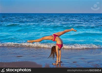 acrobatic gymnastics bikini girl in a beach blue shore at summer