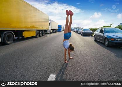 Acrobatic hand stand girl in a traffic jam road having fun. Hand stand girl in a traffic jam road