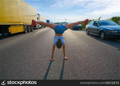 Acrobatic hand stand girl in a traffic jam road having fun. Hand stand girl in a traffic jam road