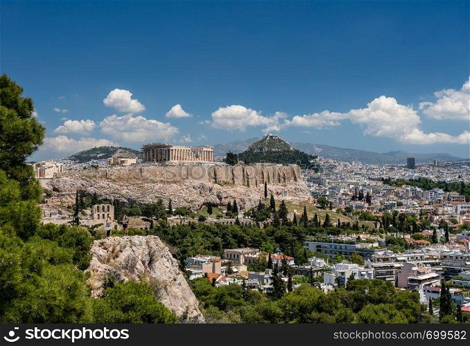 Acropolis and Lycabettus Hill framed by trees from the summit of Lycabettus hill. Panorama of city of Athens from Lycabettus hill