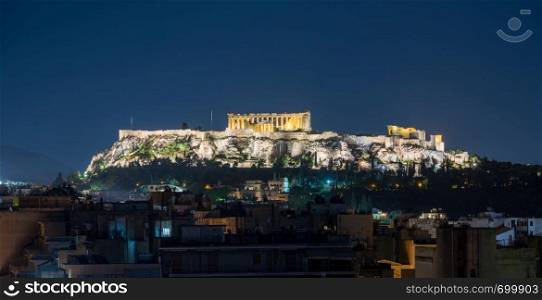 Acropolis hill at night with the city of Athens surrounding it. Acropolis hill rises above Athens apartments