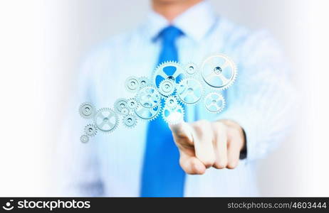 Activate working mechanism. Close up of businessman touching gears mechanism with finger