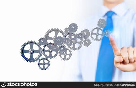 Activate working mechanism. Close up of businessman touching gears mechanism with finger