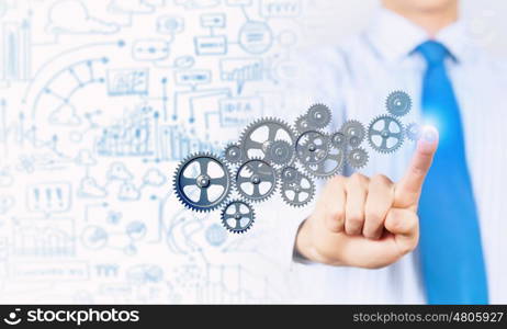 Activate working mechanism. Close up of businessman touching gears mechanism with finger