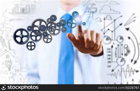 Activate working mechanism. Close up of businessman touching gears mechanism with finger