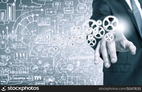 Activate working mechanism. Close up of businessman touching gears mechanism with finger