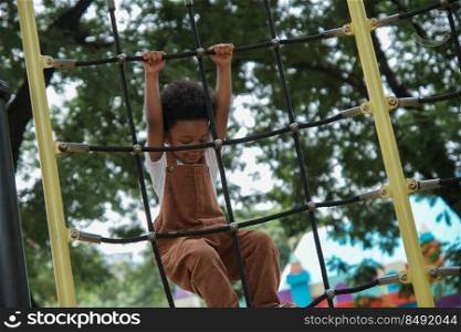 Active African little boy afro hair enjoy playing outdoors, 3 Years kid having fun climbing rope on playground in the park on a sunny day, front view