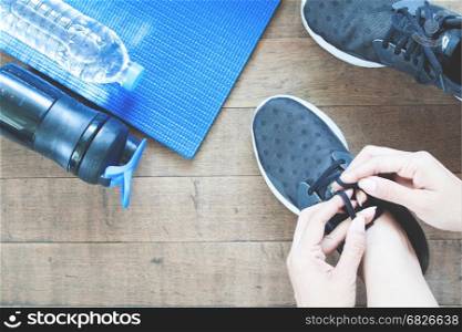 Active female hand with sport and working out equipments, flat lay on wooden floor