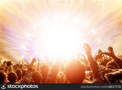 Active happy people enjoying rock concert, many lights from the stage where playing famous musical band, night entertainment concept