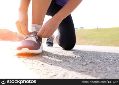 Active healthy woman tying running shoes,  jogging runner healthcare and well being concept