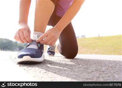 Active healthy woman tying running shoes, jogging runner healthcare and well being concept