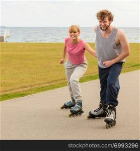 Active lifestyle people and freedom concept. Young fit couple on roller skates riding outdoors on sea coast, woman and man enjoying time together.. roller skater couple skating outdoor