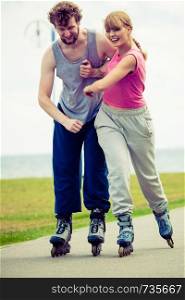 Active lifestyle people and freedom concept. Young fit couple on roller skates riding outdoors on sea coast, woman and man enjoying time together.. roller skater couple skating outdoor