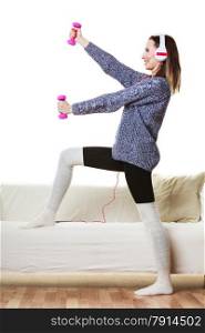 Active lifestyle, relax concept. Fit woman listening to music while doing exercise with dumbbells at home
