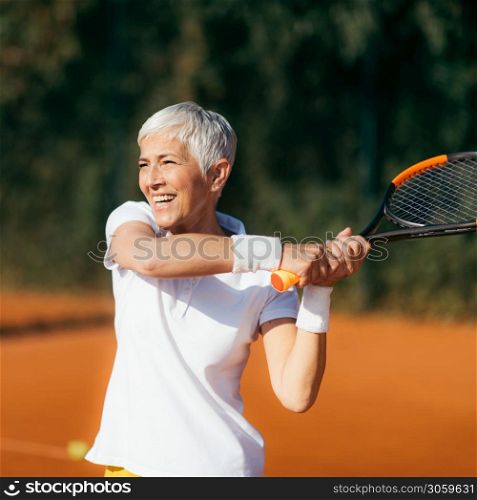 Active Lifestyle Seniors ? Positive Mature Woman Playing Tennis Recreationally