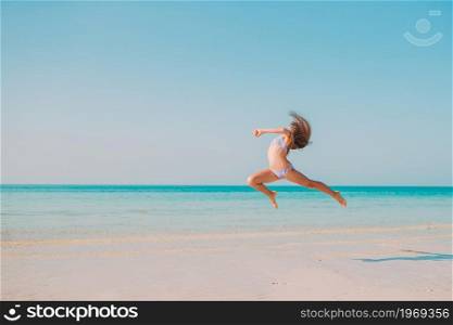 Active little girl on the beach having a lot of fun in shallow water. Adorable active little girl at beach during summer vacation