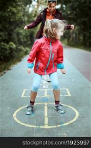 Active little girl playing hopscotch on playground outdoors. Jumping for joy. Children outdoor activities