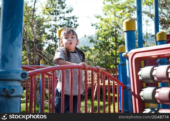 Active little girl running in the outdoor playground in the park. Happy child girl having fun on children playground. Play is learning in childhood.