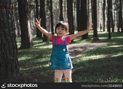 Active little girls running in the pine forest on a warm summer day. Happy girl smiles and laughs while spending time with her family in the park on vacation.