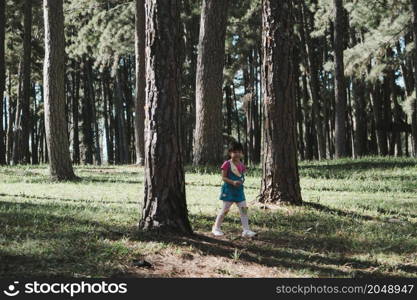 Active little girls running in the pine forest on a warm summer day. Happy girl smiles and laughs while spending time with her family in the park on vacation.