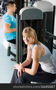 Active man and woman at fitness center exercise on machine