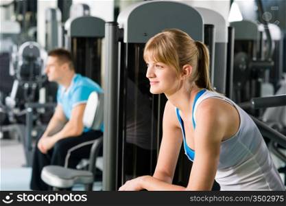 Active man and woman at fitness center exercise on machine