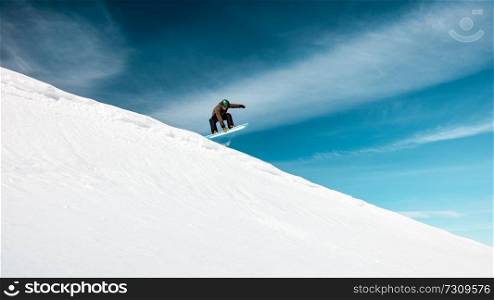 Active man on snowboard in snowy mountains over blue sky background, happy healthy lifestyle, extreme winter vacation