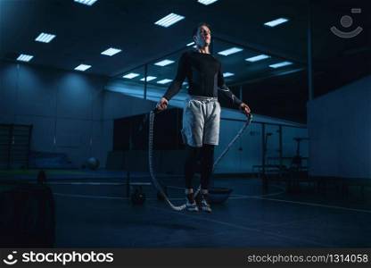 Active man on training, workout with rope in gym. Energy exercises in sport club. Active man on training, workout with rope