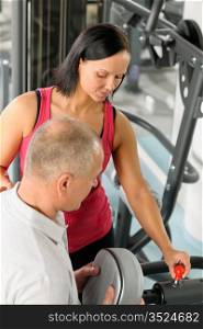 Active man watch personal trainer adjust machine level at gym