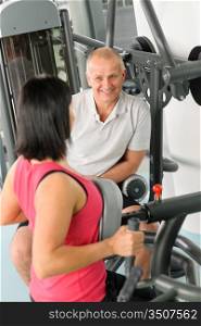 Active man watch personal trainer show exercise on gym machine