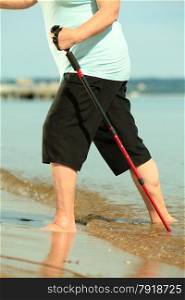 active mature lifestyle. barefoot senior nordic walking on a sandy beach sea shore.